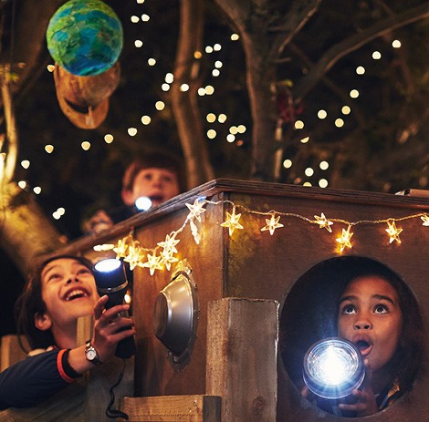 Children having fun with a torch amidst the festive glow of Christmas lights.